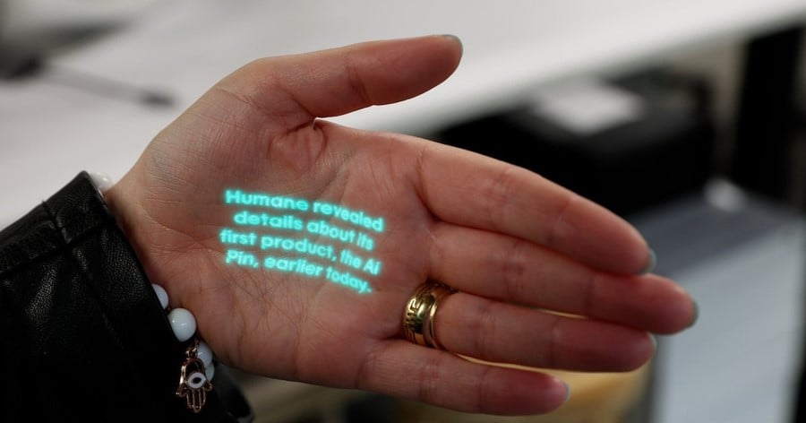 The Humane AI Pin projecting a few lines of glowing text onto a person's open palm.