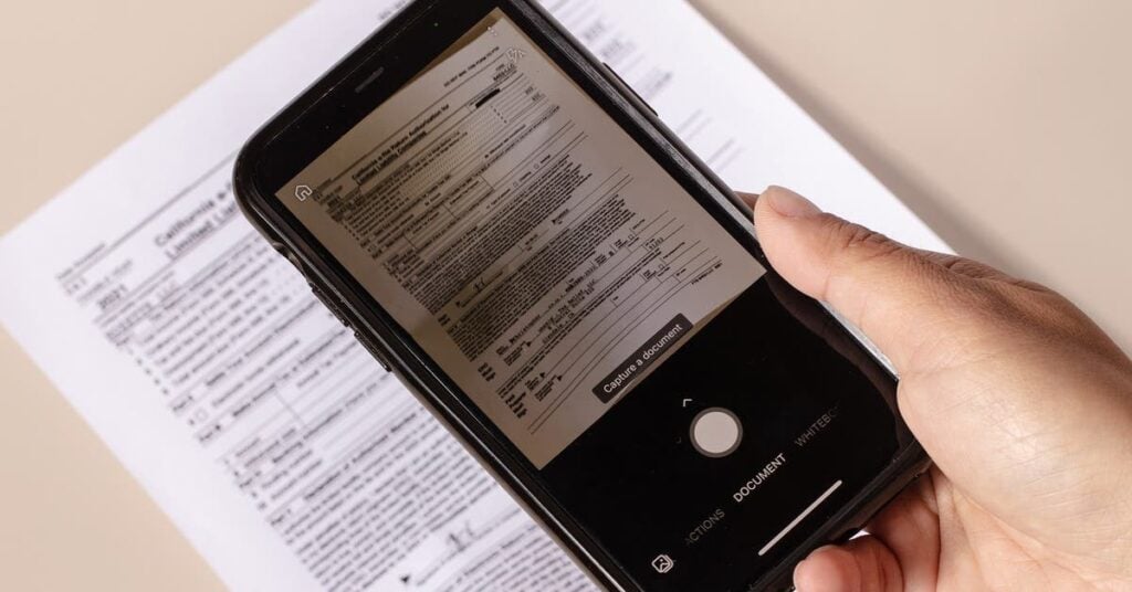 a phone being held over a document with the document on screen, showing document scanning software